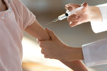Close up of female nurse give injection to little sick child patient in hospital, woman doctor or...