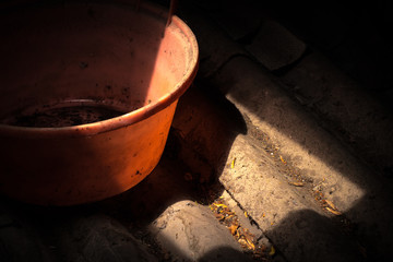 Old worn red bucket standing in a foggy environment on the attic. Red bucket lit by a ray of light from the attic window.