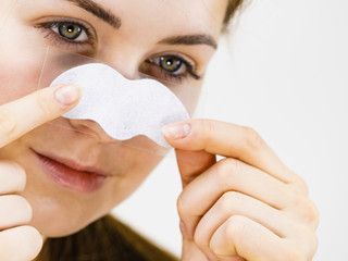 Woman applying pore strips on nose