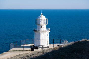 Fototapeta na wymiar White lighthouse against the blue sea.