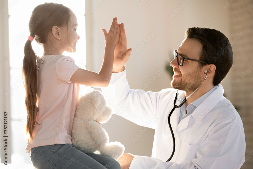 Wall mural little girl child give high five greeting with positive male doctor or gp at consultation in clinic,