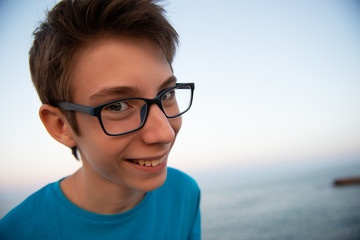 Funny young happy boy laughs looking at the camera, beach at the evening, wide angle. Beautiful...