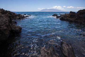 Fototapeta na wymiar Rocky Channel that leads out to the ocean with an island in the distance in Hawaii