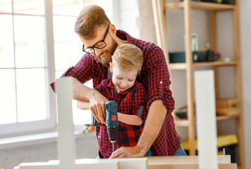 Happy kid helping father in carpentry studio.