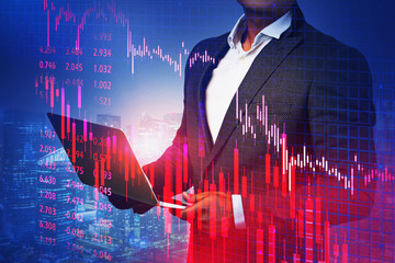 Trader with laptop in night city, falling graph