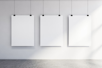 Three vertical mock up posters on white wall