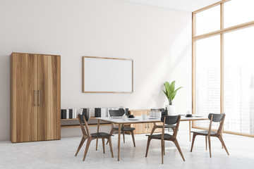 White dining room corner, bookshelf and poster