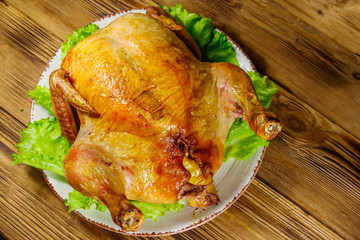 Baked whole chicken on a wooden table. Top view