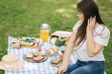 Woman vegan picnic outdoors. Female take vegan sandwich with fresh vegetables. Space for text. Vegan picnic concept