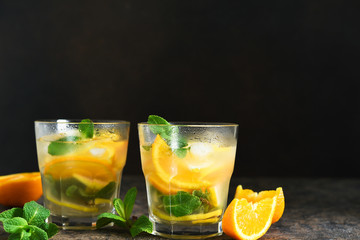 Summer drink. Cold lemonade with lemon, orange and mint on a concrete background. Horizontal focus.