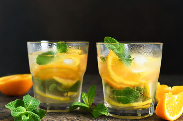 Summer drink. Cold lemonade with lemon, orange and mint on a concrete background. Horizontal focus.
