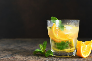 Summer drink. Cold lemonade with lemon, orange and mint on a concrete background. Horizontal focus.