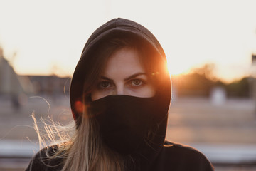 Girl in black medical mask on sunset background.