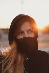 Portrait of Girl in black medical mask on sunset background.