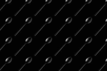 isolated black tea spoon on black background pattern horizontal