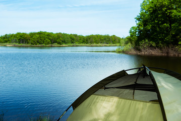 view of the lake with a tent in the frame on a summer sunny day