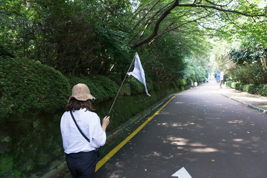 Local Guide With Guided Flag  Leads The Group Of Tourist Walk Through The Garden In  The Haeundae Dongbaekseom Island In Busan, South Korea.