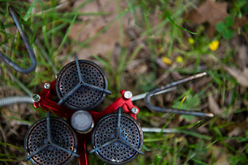 tourist gas burner of red color on the ground with green grass in natural conditions ready to use