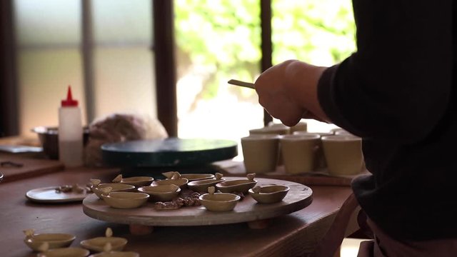 Female potter sands her works.