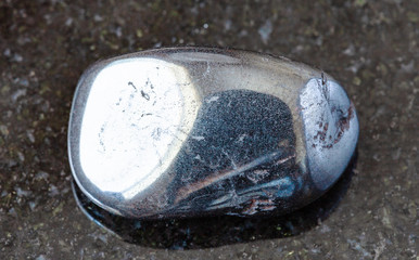 closeup of sample of natural mineral from geological collection - polished Hematite rock on black...