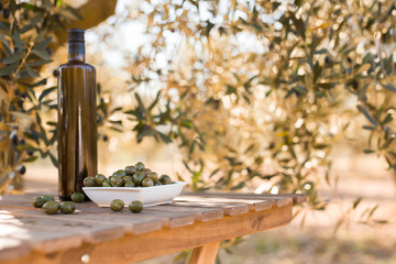 green olives and oil on table in olive grove