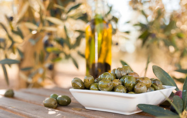 green olives and oil on table in olive grove