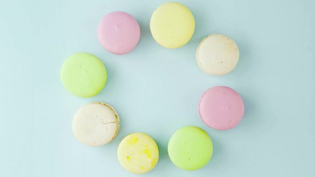 Macaroons or macaron on pastel blue surface with coffee in red cup.
