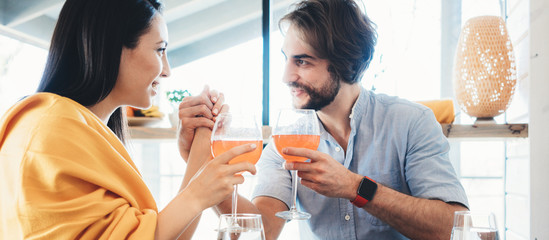 Romantic couple have dinner at home with lots of food on the table, drinking wine and cheering. Wide screen panoramic