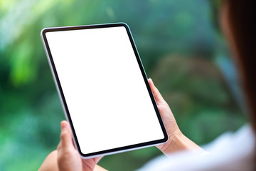 Mockup image of a woman holding black tablet pc with blank white desktop screen , green nature...