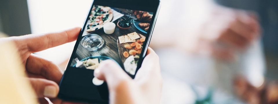 Tasty and delicious food for lunch on the table for couple spending time at home. Close-up woman taking picture to share social network. Wide screen panoramic