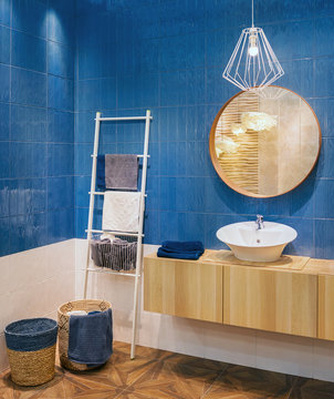 The modern interior of the washroom. A combination of blue ceramic tiles and natural wood bathroom furniture