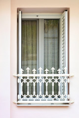 Modern metal-plastic balcony doors with lattice shutters and a dense curtain from the penetration of sunlight and a metal decorative grille at the bottom.