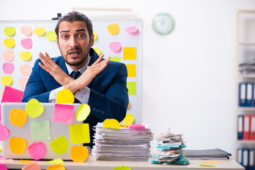 Young male employee in conflicting priorities concept