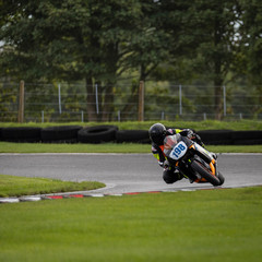 A shot of a racing bike speeding round corners on a racetrack.	