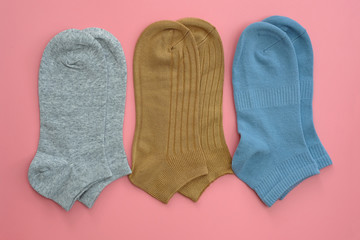 short socks of gray, brown and blue top view. Cotton socks for sports on a pink background. Set of 3 pairs of socks below the ankles in different colors. Fashionable clothes for sports and active life