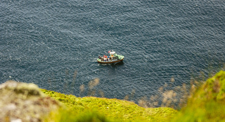 Tourists are photographing birds from a fishing boat at Runde bird island in Alesund, Norway.