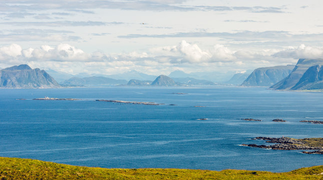 Panorama view from Runde island in Alesund, Norway towards the ocean and beautiful mountain scenery in the background during sunny day in summer.