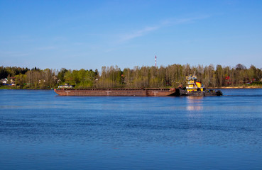 A tug pushing a heavy barge on the spring river.