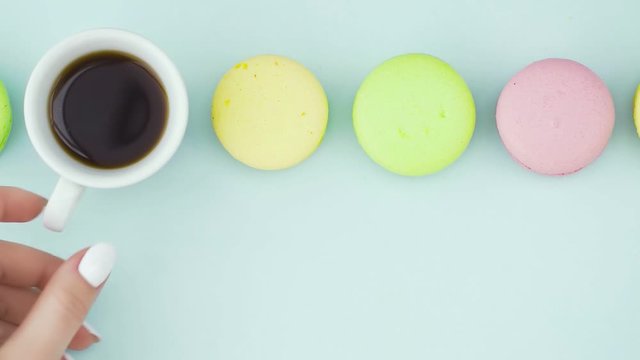 Macaroons or macaron on pastel blue surface with espresso in white cup.
