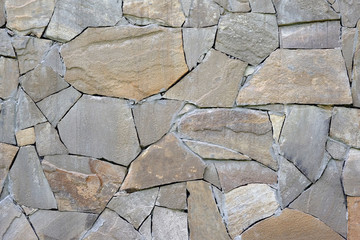 Abstract gray stone background. Mosaic pattern of old brown stones on the facade of the house. Rock texture closeup. Masonry finish on the basement of the building. stone wall cladding