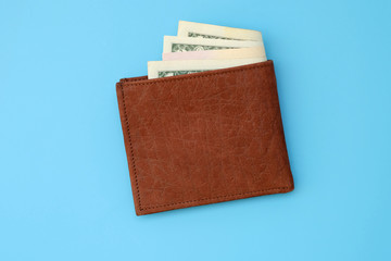 Brown leather men's wallet top view. Money in a wallet on a blue background. Concept of budgeting, finance planning.