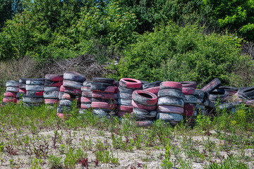 Dump of old tires of automobile wheels. Old wheel protectors. Old tyres polluting the nature. Environmental pollution.