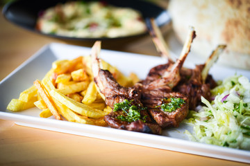 delicious grilled lamb chopsticks with french fries, pesto sauce & mix of lettuces
