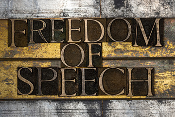 Photo of real authentic typeset letters forming Freedom of Speech text with on vintage textured silver grunge copper and gold background