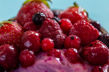 Close up of frozen berries on a cyan background. Cold summer fruit close-up.