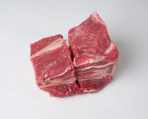 Pieces of fresh raw meat and beef bones on a white background. Ingredients for cooking