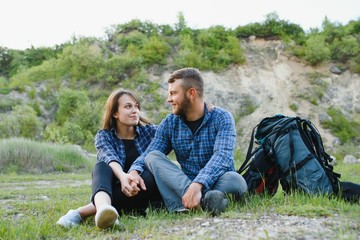 Couple enjoying beautiful views on the mountains, while traveling with backpacks in the mountains during the summer vacations