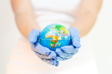 Earth globe held with hands covered with surgical gloves representing global protection against the spread of disease and coronavirus  and       nature  protection  .