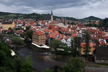 Fototapeta na wymiar Panorama of tiled roofs of buildings of the historic part of Cesky Krumlov. View of the ancient bridge over the Vltava, the embankment and St. Vitus Church.