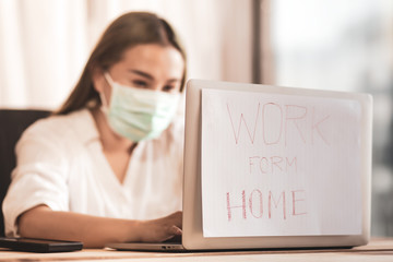 blurred of young woman are working on laptops. handwriting text  paper noted stick on laptops work from home. be a role model for everyone..Stay home. Quarantine. World pandemic..